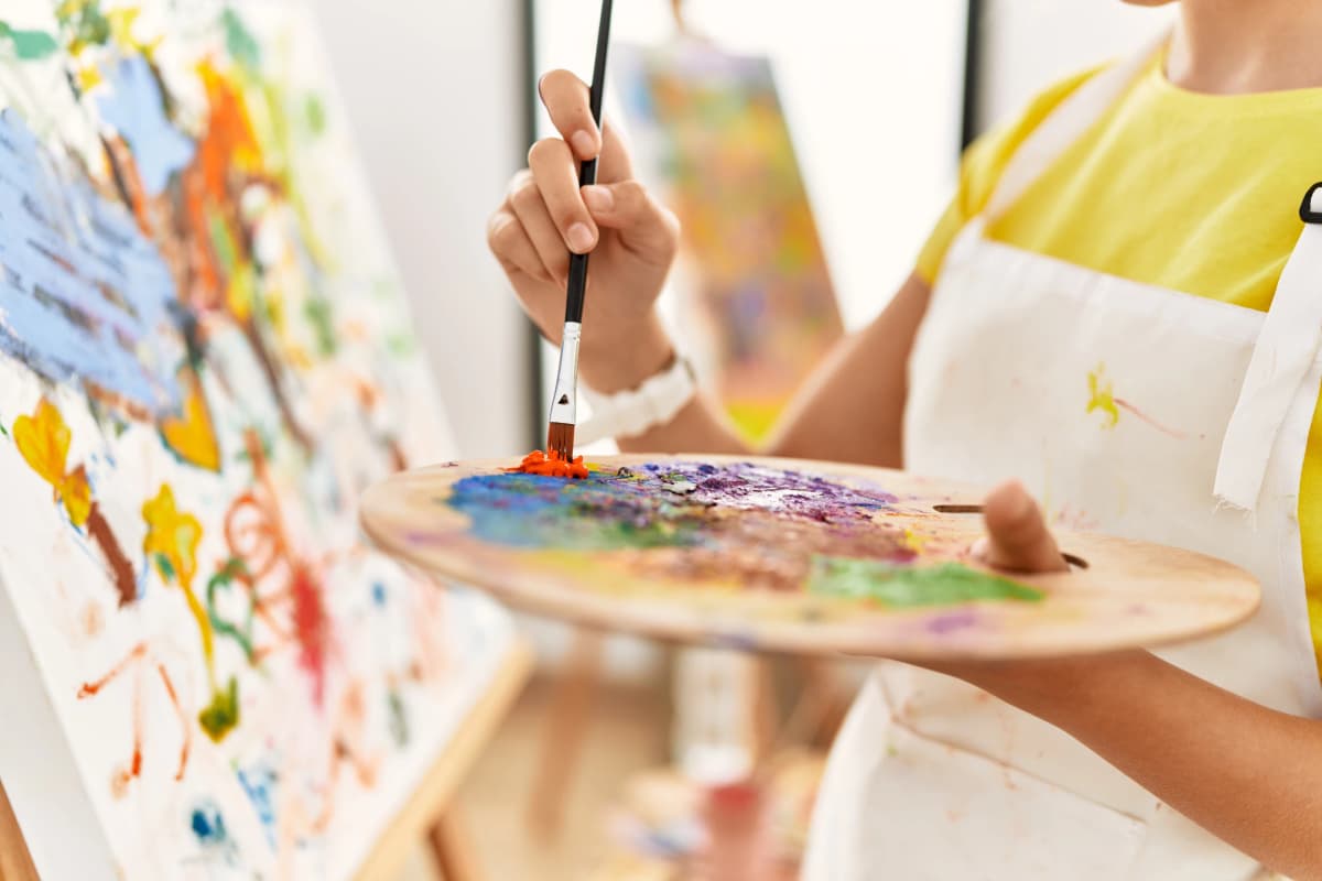 Child painting on canvas during art and creativity workshop at camp
